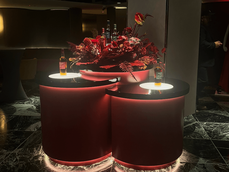 Glendronach whisky display stand with illuminated red counters and floral arrangement